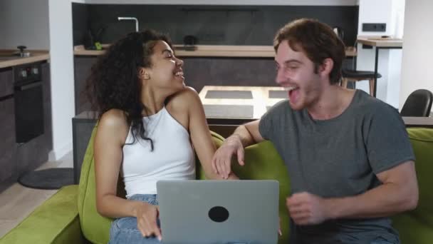 Opgewonden dolblij multiraciale paar kijken naar het scherm van laptop voelen winnaars verrast door loterij weddenschappen winnende bod. Vriend en vriendin vieren internet loterij overwinningsprijs goed nieuws — Stockvideo