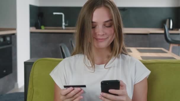 Young woman shopping online on sofa at home. Smiling woman online banking using smartphone shopping online with credit card at home lifestyle. Easy pay using digital gadget. — Stock Video