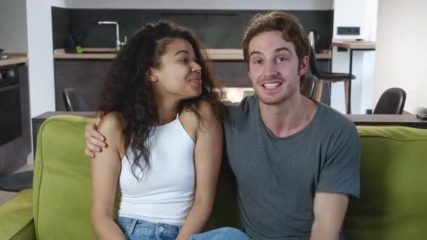 Ευτυχισμένο νεαρό διαφυλετικό ζευγάρι που κάνει βιντεοκλήση για να ανακοινώσει το γάμο του στο σπίτι. Χαμογελώντας νεαρός άνδρας και γυναίκα κουνώντας και μιλώντας στην κάμερα, στη συνέχεια δείχνει δαχτυλίδι αρραβώνων — Αρχείο Βίντεο