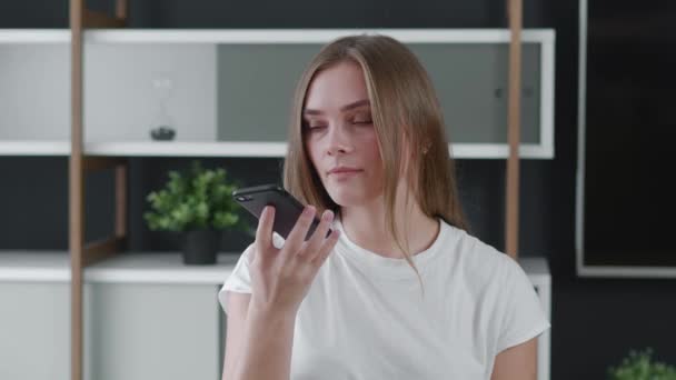 Giovane donna che registra messaggi audio su smartphone nei social network per gli amici. Attraente ragazza millenaria che attiva assistente virtuale sul telefono cellulare a casa ufficio. — Video Stock