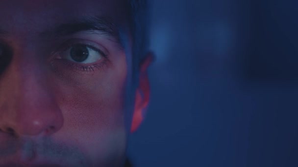 Detailní odraz v oku světla z obrazovky. Makrooči mladého muže, který se v noci dívá na film. Rychlý přenos zpráv. — Stock video