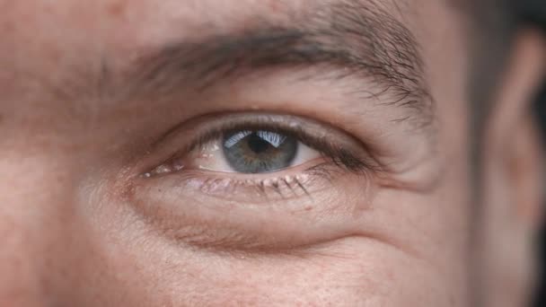Großaufnahme eines lächelnden Auges, das in die Kamera blickt. Makroauge positiver glücklicher männlicher Nahaufnahme. — Stockvideo