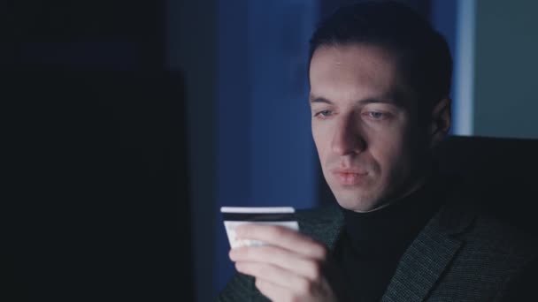 Młody człowiek przedsiębiorca przy użyciu laptopa komputerowego i zakupy online z karty kredytowej podczas siedzenia w miejscu pracy późno w nocy. — Wideo stockowe