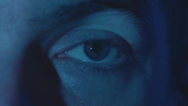 Detailní odraz v oku světla z obrazovky. Makrooči mladého muže, který se v noci dívá na film. Rychlý přenos zpráv. — Stock video