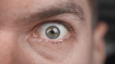 Aşırı derecede yaklaşan şaşırmış erkek gözünü açar ve kameraya bakar. Korkmuş adam şok reaksiyonu makro göz.