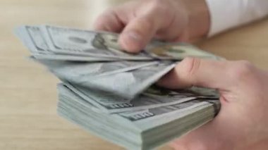 Kapatın, adam ellerini para sayıyor, Amerikan doları banknotları. Zaman aşımı.