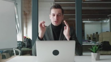 Ofiste otururken bilgisayarını kullanarak gülümseyen bir iş adamı. Video konferansında konuşan yakışıklı adam. Webcam şirketi toplantı konsepti.