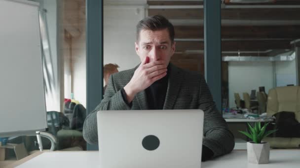 Напружений бізнесмен шокований під час роботи в ноутбуці в офісі. Неприємно здивований і наляканий бізнес Чоловік переживає читання поганих новин на комп'ютері. кризової концепції . — стокове відео