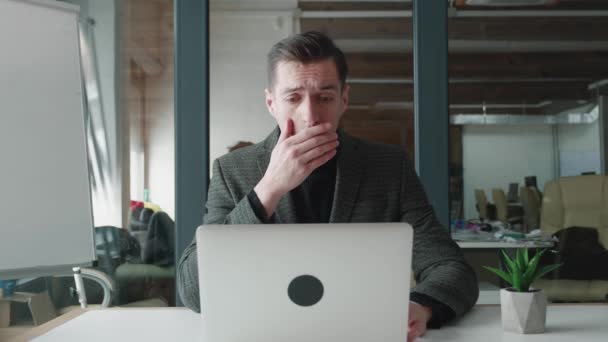 Afraid and shocked business man looking at monitor screen, cover his mouth with his hand while working at computer laptop at office. Male scared of bad news, read terrible message. Crisis concept. — Stock Video