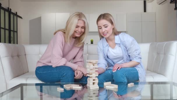 Hija adulta y su madre mayor jugando al juego de mesa, disfrutando de la actividad de ocio. Familia femenina multigeneracional jugando juego de eliminación de bloques juntos en casa. — Vídeos de Stock