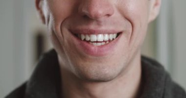 Dişleriyle gülümseyen erkek ağzını kapat. Genç adam içeride gülümsüyor, makro çekim. Gülümseyen adamın ayrıntıları..