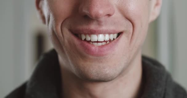 Feche a boca masculina de sorrir com os dentes. O jovem está a sorrir dentro de casa, macro shot. Detalhe de um cara de sorriso. — Vídeo de Stock