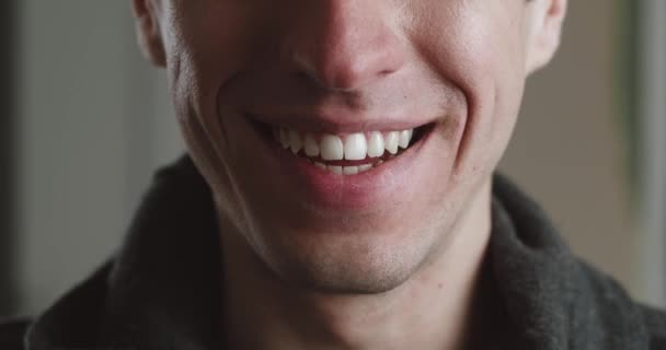 Feche a boca masculina de sorrir com os dentes. O jovem está a sorrir dentro de casa, macro shot. Detalhe de um cara de sorriso. — Vídeo de Stock