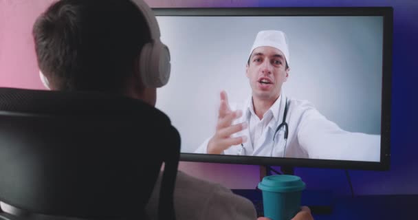 Οπίσθια όψη του νεαρού άνδρα βλέποντας βίντεο online συνέδριο με το γιατρό. Μόνος υπομονετικός άντρας συμβουλεύεται γιατρό σε online chat αργά το βράδυ. — Αρχείο Βίντεο