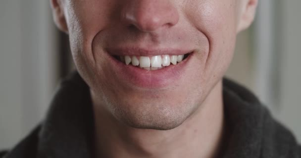 Feche a boca masculina de sorrir com os dentes. O jovem está a sorrir dentro de casa, macro shot. Detalhe de um cara de sorriso. — Vídeo de Stock