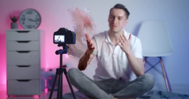 Retrato de videoblogger masculino filmando novo vídeo vlog com câmera profissional enquanto sentado no chão em casa — Vídeo de Stock