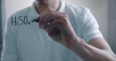 Kendinden emin, odaklanmış ciddi bilim adamının siyah kalem kullanarak saydam cam duvar tahtasına kimyasal formül yazıp projeyi analiz etmesinin zamanı..