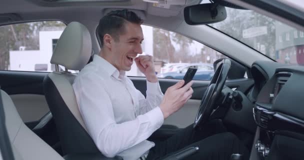驚きの興奮ビジネスマンの勝者は車の中で座っている間に携帯電話のオンラインベットの入札ゲームの勝利に驚いて良いニュースを読むスマートフォンを保持. — ストック動画