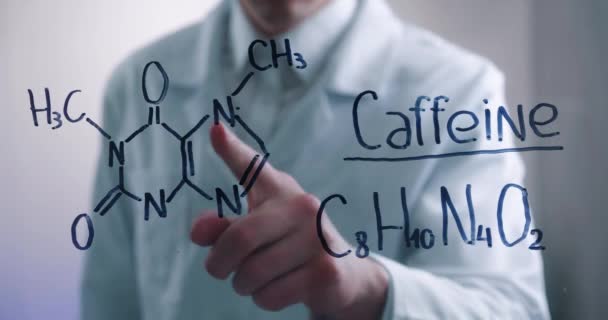 Man scientist thinks over the solution of chemical formula of caffeine, drawn on a glass board in a laboratory. Male biochemist solves the problem. — Stock Video