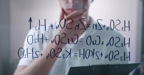 Homem cientista pensa sobre a solução de fórmulas químicas, desenhado em uma placa de vidro em um laboratório. Químico masculino resolve o problema. — Vídeo de Stock