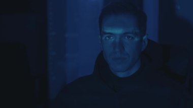 Bilgisayar üzerinde çalışan bilgisayar programcısı geceleri sunucuya siber saldırı. Ekrandan yansıyan ışık yüzüne yansıdı. Karanlık Veri Merkezi 'ndeki tehlikeli erkek sanal hackleme yazılımı.