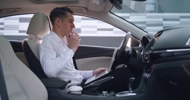 Retrato de jovem homem de negócios conversando por videoconferência usando laptop enquanto sentado no carro. Homem empresário cumprimenta por vídeo chat, conceito de trabalho remoto. — Vídeo de Stock