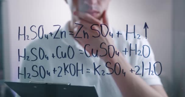 Mand videnskabsmand tænker over løsningen af kemiske formler, tegnet på et glas bord i et laboratorium. Mandlig kemiker løser problemet. – Stock-video