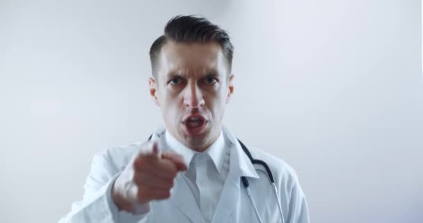 Sinirli bir doktorun çalışanlara bağırıp azarlaması, parmaklarıyla tehdit etmesi ve kameraya agresif bir şekilde bağırması.. — Stok video