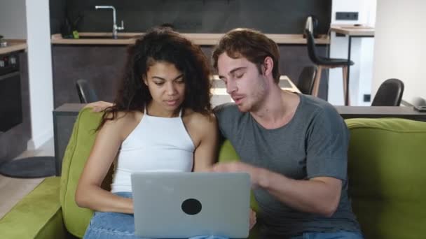 Cuplu certuri în timp ce utilizați laptop-ul în timp ce stați pe canapea acasă. Conflict familial, neînţelegere. Bărbatul și femeia au diferențe . — Videoclip de stoc
