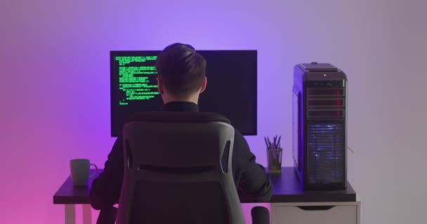 Rückansicht des Mannes Programmierer Programmierung Netzwerk-Sicherheits-Software drinnen in Neonröhren in der Nacht. Hacker tippen Code auf Computerbildschirm im dunklen Büro — Stockvideo