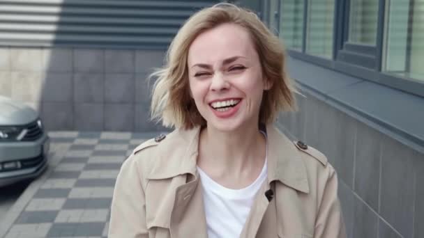 Mulher bonita feliz rindo e olhando na câmera. Jovem Positivo Carefree Feminino Sorrindo e Fazendo Grimaces, Saltando e Aproveitando o Tempo de Diversão, Em pé ao ar livre perto de Edifício de Escritório — Vídeo de Stock