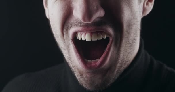 Detailní záběr vzteklého smíchu. Makro záběr na ústa šíleného naštvaný muž se zlověstně usmívá na černém pozadí — Stock video