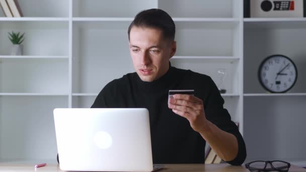 Portré üzletember kezében hitelkártya és a laptop használata, miközben fizet a megrendelés webshopban, miközben ül a munkahelyen az irodában, és csinál online vásárlás — Stock videók