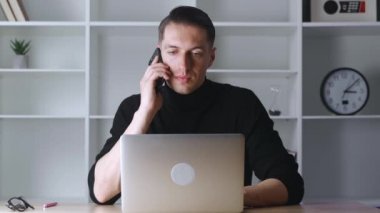 Modern ofiste cep telefonuyla konuşan kendinden emin iş adamının portresi. Neşeli erkek girişimcinin iş yerinden telefon görüşmesi yapması yakındır..