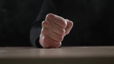 Yakından bakan adam karanlık arka planda saldırganlık göstererek yumruğunu masaya vurur. Öfke kavramı.