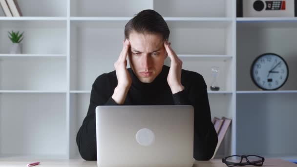 Sad man freelancer looking stressed out while working on his laptop worried about problems while sitting at modern office. Portrait of overworked crying businessman while working with computer — Stock Video