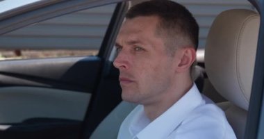 Şoför koltuğunda oturan olgun CEO 'nun portresi. Otomobil direksiyonunun başında kendinden emin bir işadamı oturuyor. 40 'lı yaşlarda beyaz gömlek giyen bir erkek sürücü. Sabit çekim