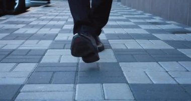 İşe gidip gelen bir iş adamının önü. Deri ayakkabılı ve takım elbiseli kendine güvenen bir girişimci iş yerinin caddesi boyunca yürür.