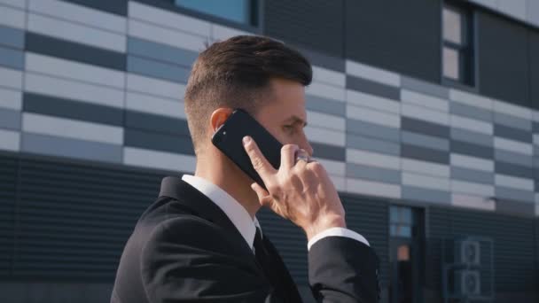 Retrato de empresario confiado en traje clásico hablando por teléfono al aire libre. Joven hombre de negocios teniendo conversación de negocios. — Vídeos de Stock