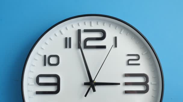 Κοντινό πλάνο ενιαίο λευκό ρολόι γραφείου κρέμεται σε ένα μπλε χρώμα τοίχο. — Αρχείο Βίντεο