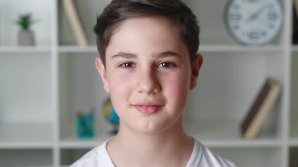 12-13歳の幸せな男の子の肖像画白いシャツのカメラを見て、自宅で笑顔で。ハンサムなティーンエイジャーの男の子、クローズアップ — ストック動画