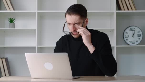 Portret van een geschokte zakenman die naar een laptop kijkt, een bril afdoet en zegt wat. Verrast en bang man op moderne kantoor interieur achtergrond. verontwaardigde en afwijkende man zeggen nee met walging — Stockvideo