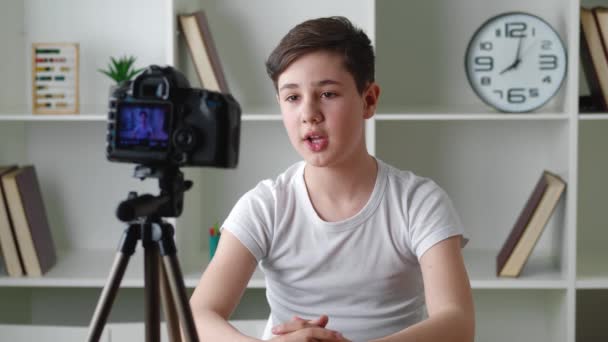 Портрет мальчика-видеоблоггера 13 лет, снимающего новое видео видеоблога с профессиональной камерой дома. Красивый подросток-блогер записывает видео фильм для интернета. Молодой блогер говорит на видео съемки — стоковое видео