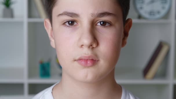 Gros plan d'un garçon de 12-13 ans en chemise blanche regardant la caméra à la maison. Visage portrait de beau adolescent écolier à l'intérieur — Video