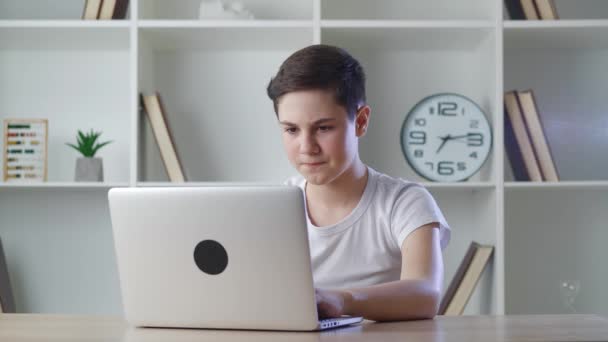 Menino chocado de 13 anos se alegra com as conquistas de trabalhar em um computador em casa. Adolescente é agradavelmente surpreendido pela vitória repentina ao jogar com seu laptop. — Vídeo de Stock