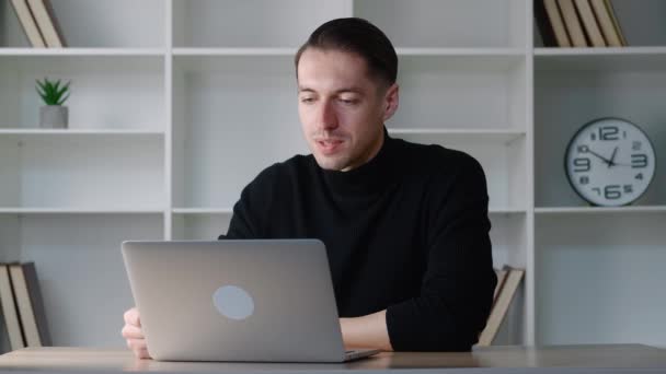 Genç iş adamı modern ofiste otururken bilgisayarını video konferansı için kullanıyor. Video görüşmesinde konuşan yakışıklı bir adam. Webcam şirketi toplantı konsepti. — Stok video