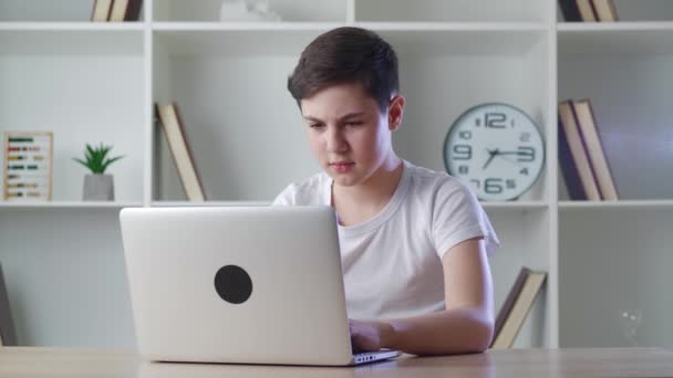 Verängstigter Junge schockiert über schreckliche Szene, während er Horrornachrichten auf dem Computer liest. Ängstliches Schulkind auf Monitor schauen, Mund mit der Hand bedecken, während es zu Hause am Schreibtisch sitzt. — Stockvideo