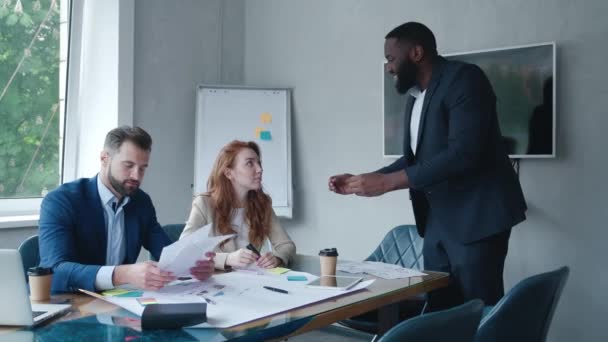 Motivated african american team leader explaining company development strategy to smiling colleagues. Happy multiracial business people working together at modern office. — Wideo stockowe