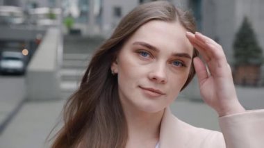 İş yerinin dışındaki kameralara bakan resmi kıyafetli genç bayan yönetici. Şehir merkezinde açık havada duran güzel bir iş kadınının portresi..