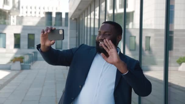 在商务中心附近，非裔美国商人在户外用智能手机进行视频聊天。市中心身着正装的男性创业者在讲电话视频 — 图库视频影像